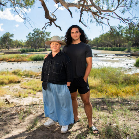 Creator Sharon Windsor standing under a tree by a river with a scenic landscape.